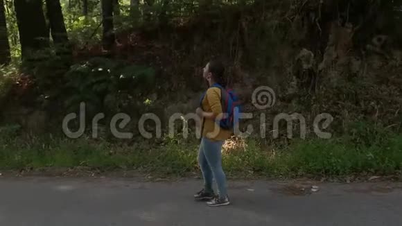 徒步旅行者女人背着背包在森林里的路上行走视频的预览图
