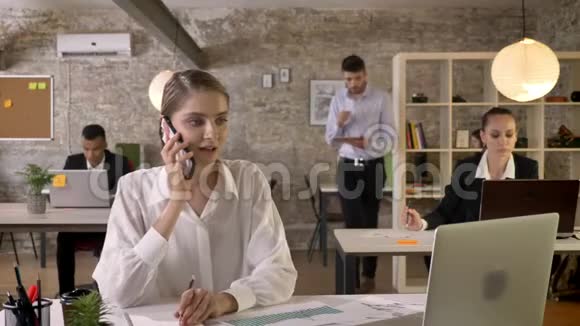 年轻严肃的女商人正在办公室里打电话写下来办公室工作人员正在与科技建立联系视频的预览图