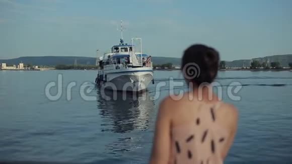 一个美丽的女孩看着一艘游轮接近码头的后景视频的预览图