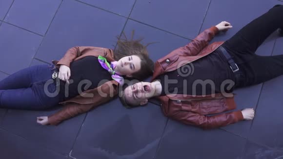 穿着浅棕色夹克的漂亮男孩和女孩躺在深色瓷砖地板上视频的预览图