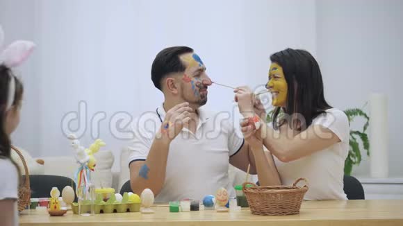 可爱的夫妇在复活节画笔的帮助下彼此着色突然他们注意到他们的女儿视频的预览图