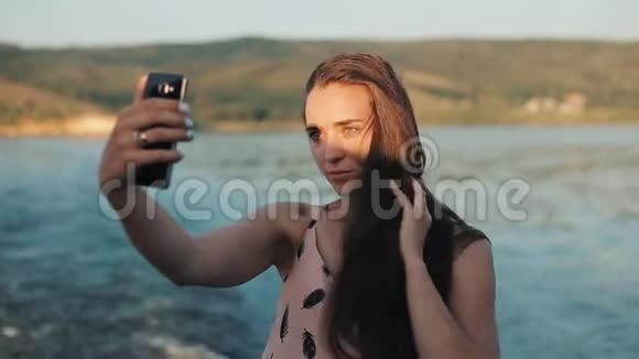 一个头发松松的美丽女孩的半身像在河边的山上拍了一张自己的照片视频的预览图