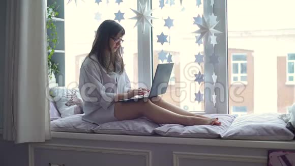 在窗台上用笔记本电脑的女人视频的预览图