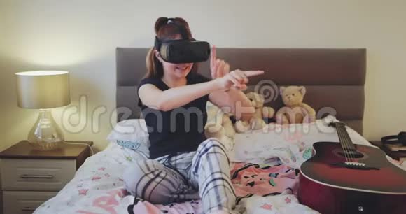 在十几岁的卧室里一位年轻女士在床上玩虚拟现实眼镜非常热情和有魅力视频的预览图