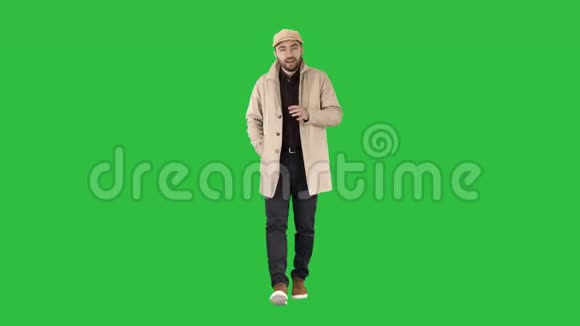 会说话的年轻人穿着风衣自信地与相机交谈只需在绿色屏幕上前进Chroma键视频的预览图
