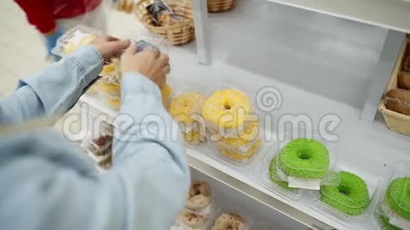 妇女在糕点组购买甜甜圈视频的预览图