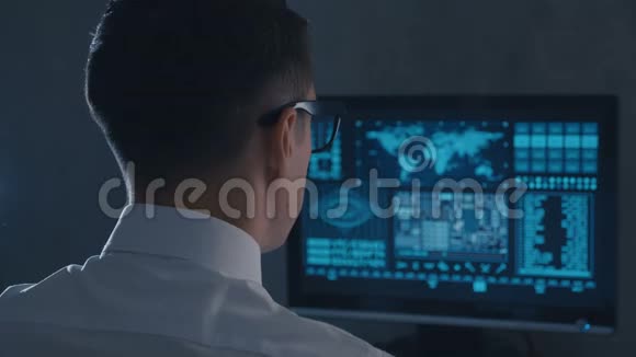 在数据中心工作的戴眼镜和穿白衬衫的男程序员的后视图视频的预览图