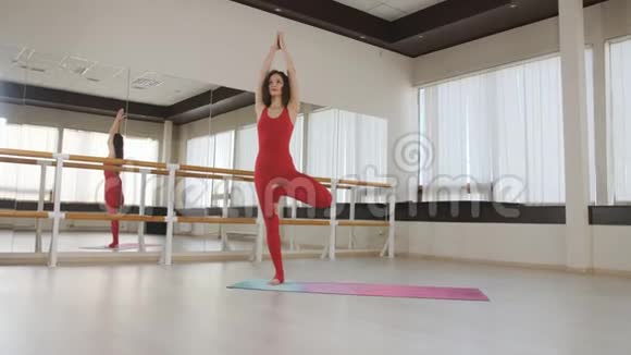 女孩在大厅里的一个特殊垫子上做瑜伽体式练习上面有一面大镜子视频的预览图