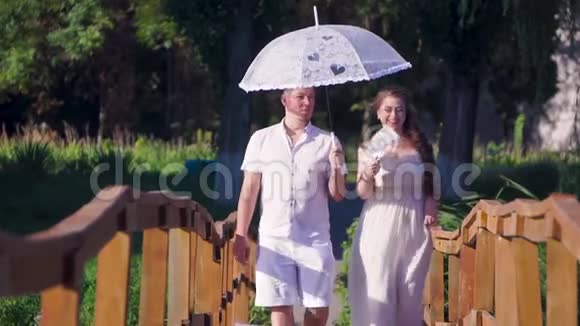 恋爱中的男女手拿雨伞走在桥上视频的预览图