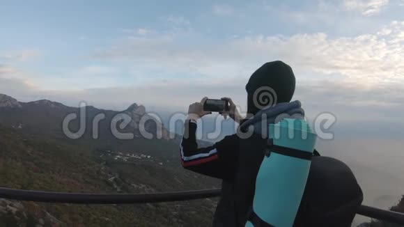 山顶上的女孩在手机上拍照的女游客年轻女性旅行者的背景视频的预览图