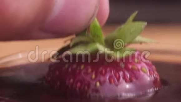 一个男人在巧克力中蘸上多汁的红色成熟草莓向上举起视频的预览图