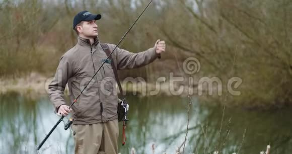 在湖边准备鱼竿的自信男子视频的预览图