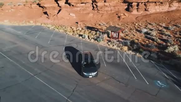 无人机绕着银色的汽车飞来飞去站在干燥的岩石沙漠中央的小公园里人们下车欣赏风景视频的预览图