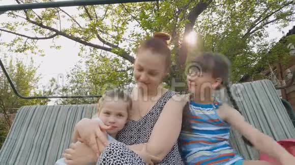 妈妈和女儿坐在花园秋千上父母和孩子的家庭关系视频的预览图