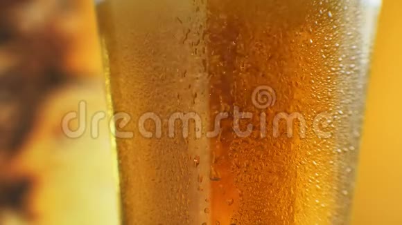 橙色液体玻璃中泡沫的宏观镜头在装有水滴的杯子里喝冷光啤酒手工艺啤酒视频的预览图