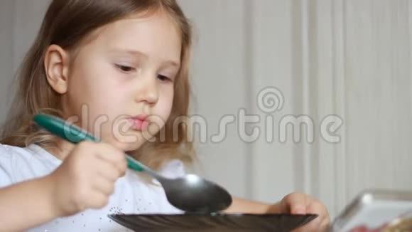 孩子用勺子吃汤贴身女婴坐在家里做饭和吃饭的桌子旁视频的预览图