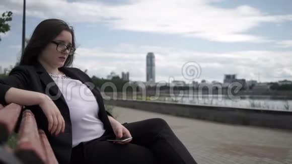 有电话的女人坐在长凳上视频的预览图