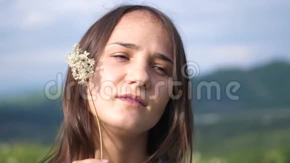 年轻漂亮的女人带着鲜花在田野里享受大自然慢动作视频的预览图