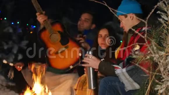一群朋友在树林里的火边玩得很开心一个年轻人打开热水瓶视频的预览图