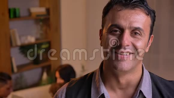 一幅阿拉伯男人的特写镜头他微笑着站在客厅里和家人在一起视频的预览图