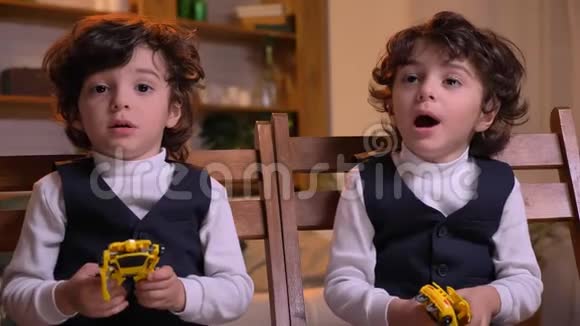 两个阿拉伯卷头双胞胎坐在客厅的椅子上聚精会神地看着镜头说话视频的预览图