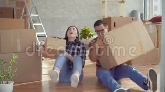 疲惫的年轻夫妇带着笔记本电脑在箱子的背景上移动视频的预览图
