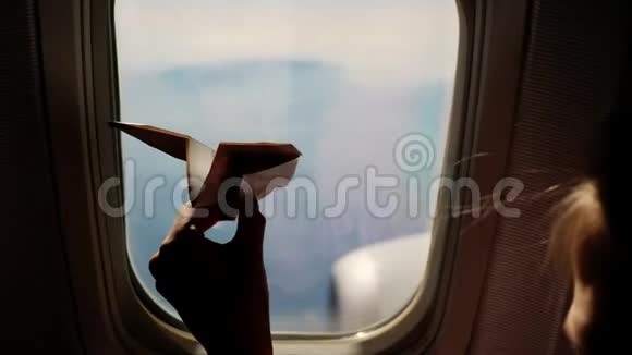 特写镜头一个孩子的手小纸飞机在飞机窗口的背景下的剪影儿童视频的预览图