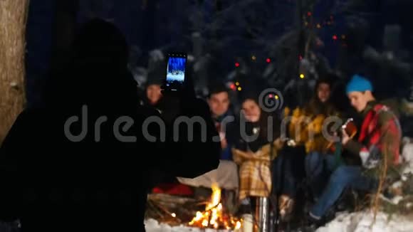 一群朋友在冬林玩得很开心坐在篝火旁一个给他们拍照的人视频的预览图
