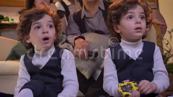 两对阿拉伯卷头双胞胎坐在客厅地板上专心看电视的画像视频的预览图