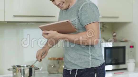 特写微笑男在家厨房做饭视频的预览图