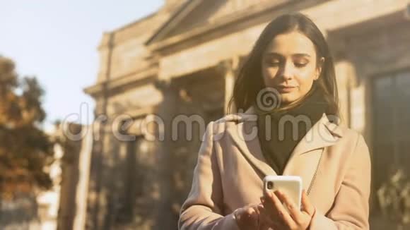 漂亮的年轻女士在智能手机上讲话站在古典建筑附近视频的预览图