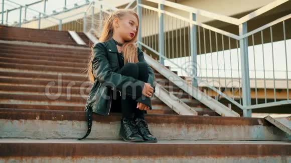 穿黑色皮夹克的摇滚女孩坐在楼梯上穿黑色皮夹克的年轻女孩坐在楼梯上视频的预览图