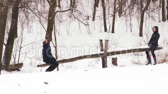 慢动作印度男人和女人在冬天的森林里骑着木秋千视频的预览图