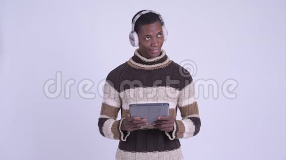 年轻快乐的非洲男人一边思考一边用数字平板电脑准备过冬视频的预览图