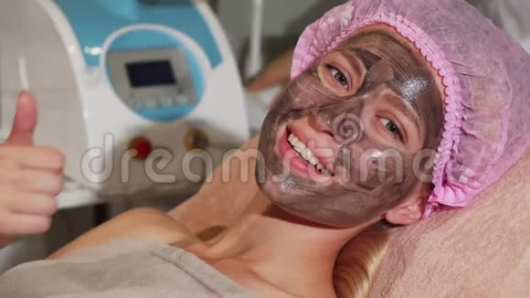 快乐的女人在脸上戴着黑色面具时竖起大拇指视频的预览图