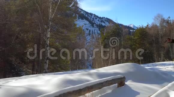 冬天旅行者在山上穿着雪鞋散步他坐在木凳上休息视频的预览图