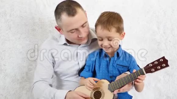 快乐的父子俩弹吉他唱歌感受幸福爱欢乐和微笑的情感视频的预览图