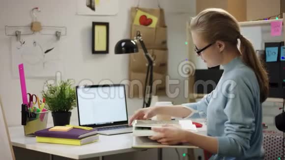 年轻女子用笔记本电脑一桌一桌地看书视频的预览图