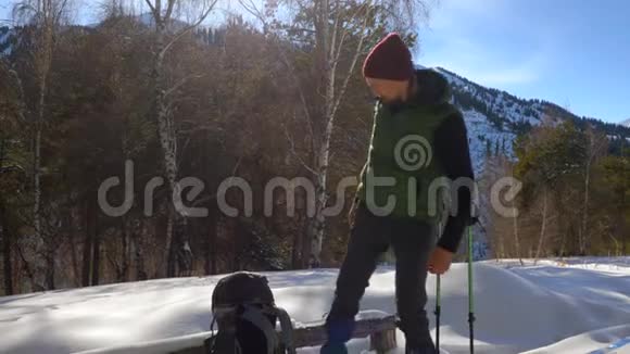 冬天旅行者在山上穿着雪鞋散步他坐在木凳上休息视频的预览图