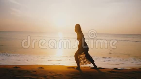 令人惊叹的拍摄年轻美丽幸福的女人行走沿着田园诗般的日落海滩微笑的镜头视频的预览图
