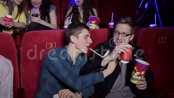 年轻人在电影院里用爆米花和饮料放松视频的预览图