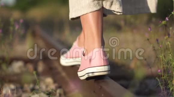 女孩沿着铁路走浪漫的慢动作追踪拍摄的年轻女孩双脚特写行走在铁路上视频的预览图