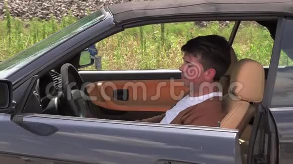 一个年轻人坐在路上一辆破车旁视频的预览图