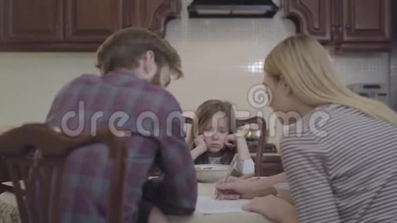 小女孩坐在父母面前伤心难过她不吃东西坐在桌旁的男女青年视频的预览图