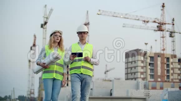 建筑经理及工程师使用平板电脑及印刷品在建筑工地行走视频的预览图