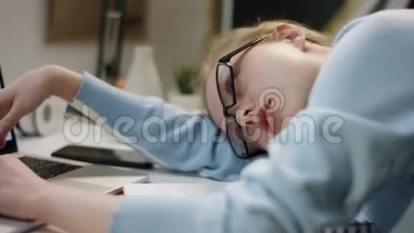 年轻漂亮的学生用笔记本电脑睡在桌子上视频的预览图