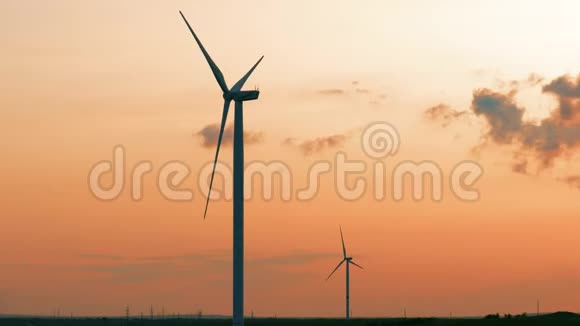 日落时麦田中的风力涡轮机日落时天空背景下的风车螺旋桨视频的预览图