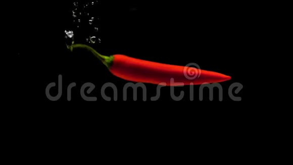 一只红辣椒在黑色背景下落入透明水视频的预览图
