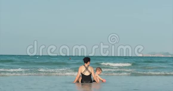 快乐和无忧无虑的母子在海边玩耍晒日光浴游泳儿童和成人在热带海域玩耍视频的预览图