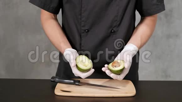 年轻的厨师穿着黑色的衣服在灰色的背景皮鳄梨用刀视频的预览图